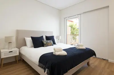 a white bedroom with a large bed with blue pillows at Mira Mar 2 - Near the beach by HD in Quarteira
