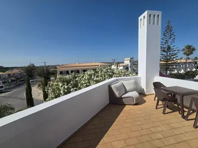 a balcony with chairs and tables on a building at Casa Madalena in Albufeira