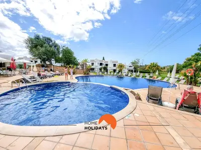 a pool at a resort with a sign that says home holidays at #121 T1 Aconchegante em Albufeira by Home Holidays in Albufeira