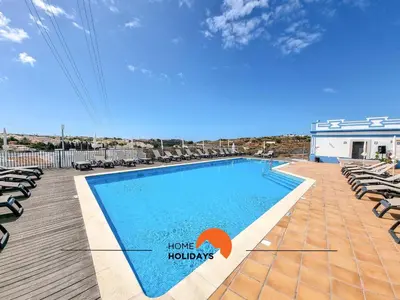 a swimming pool with lounge chairs next to a building at #121 T1 Aconchegante em Albufeira by Home Holidays in Albufeira