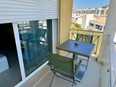 a table and chair on a balcony with a view at Apartamento Flor de Amendoeira Garden in Albufeira