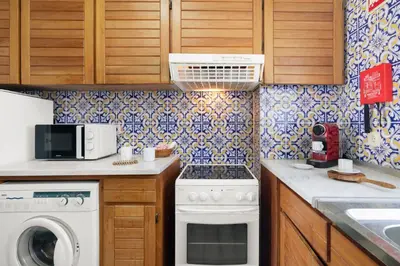 a kitchen with wooden cabinets and blue and white tiles at Casa dos Bisos in Albufeira