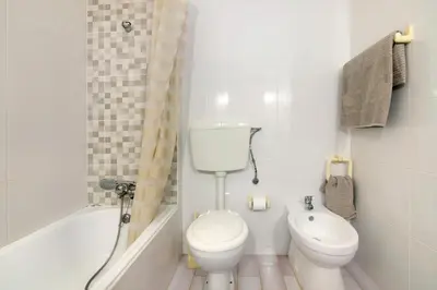 a white bathroom with a toilet and a sink at Casa dos Bisos in Albufeira