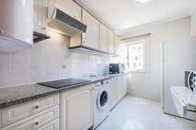 a kitchen with white cabinets and a washer and dryer at Apartment Solera in Albufeira