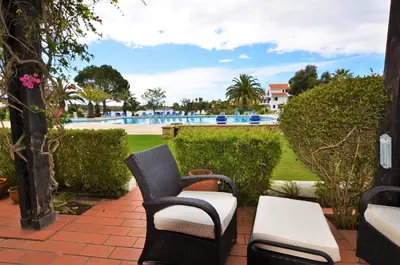 a patio with chairs and a pool in the background at Apartamento Mariana, Quinta do Lago