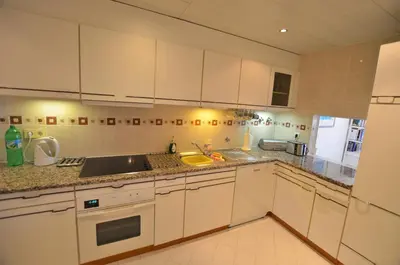 a kitchen with white cabinets and a sink at Apartamento Mariana, Quinta do Lago