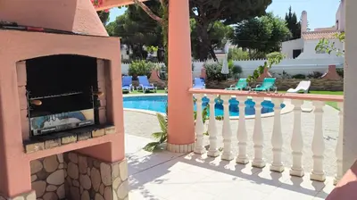 a fireplace on a patio next to a swimming pool at Vila Paraiso da Maria 5 quartos duas salas, jardim, piscina, varanda com churrasqueira e WIFI in Olhos de Água
