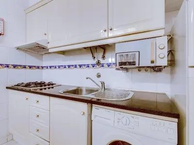 a white kitchen with a sink and a stove at Apartamento Mourasuites, T1 moderno em Vilamoura in Quarteira