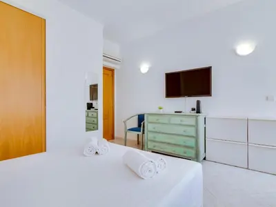a bedroom with two beds and a dresser and a tv at Apartamento Mourasuites, T1 moderno em Vilamoura in Quarteira