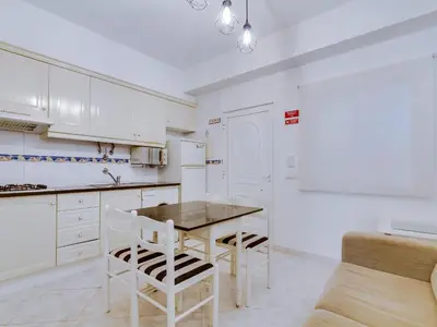 a kitchen with white cabinets and a table and chairs at Apartamento Mourasuites, T1 moderno em Vilamoura in Quarteira