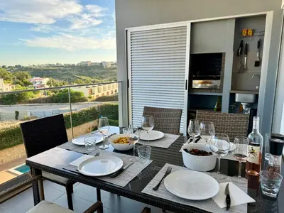a dining table with wine glasses and plates on it at Gabbiana apartment Albufeira terrace BBQ and pool in Albufeira