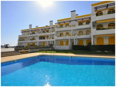 a hotel with a swimming pool in front of a building at Apartamentos Capitolina in Quarteira
