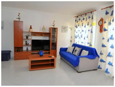 a living room with a blue couch and a tv at Apartamentos Capitolina in Quarteira