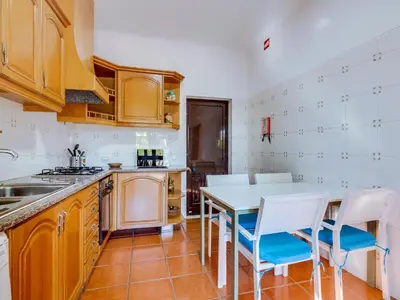 a kitchen with a table and chairs in a room at Vivenda Pereiras com 2 quartos em Quarteira in Quarteira