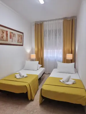 two beds in a room with yellow cushions at Happy House - Central Apartment in Faro
