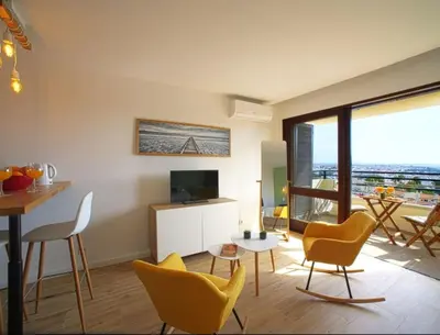 a living room with yellow chairs and a television at Sea view studio, terrace & pools - Albufeira in Albufeira