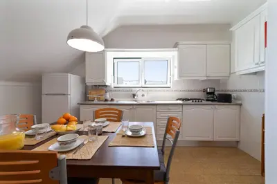 a kitchen with a wooden table and a kitchen with white cabinets at Vivenda Lemos B in Albufeira