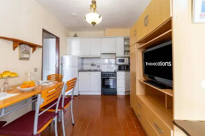 a kitchen with white appliances and a table with chairs at Vivenda Lemos D in Albufeira