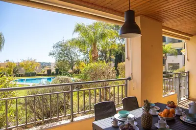 a table on a balcony with a view of a pool at Terraços do Milénio II by Garvetur in Quarteira