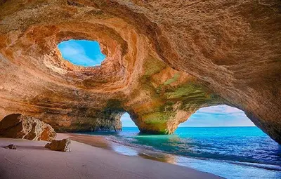 a large rock formation on a beach with the ocean at Apartamento Vida & Mar at Albufeira Beach in Albufeira