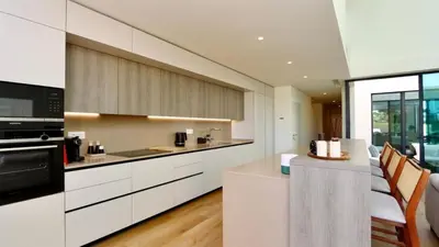 a kitchen with white cabinets and a counter with chairs at Casa Bougainvillea by CleverDetails, private pool 