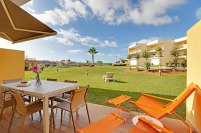 a table and chairs on a patio with a lawn at Jardins da Marina by Albufeira Rental in Albufeira