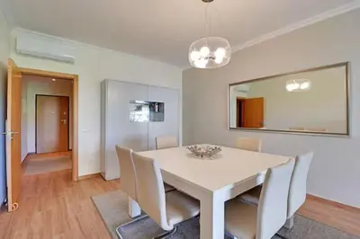 a white dining room with a white table and chairs at Jardins da Marina by Albufeira Rental in Albufeira