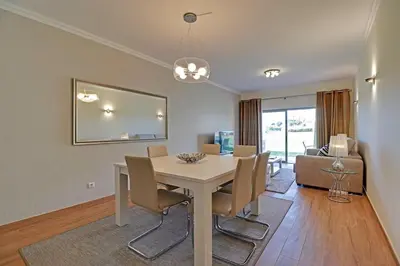 a dining room with a white table and chairs at Jardins da Marina by Albufeira Rental in Albufeira
