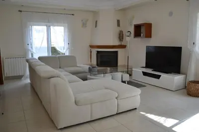 a living room with a white couch and a tv at Magnifique Villa à 10min de la mer in Faro