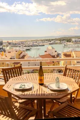 a table with two plates and a bottle of wine on a balcony at Algarve Vilamoura Quarteira vue sur Ocean-Portugal in Quarteira