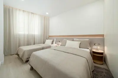 two beds in a hotel room with white walls at Townhouse with Heated Pool in Downtown Faro in Faro