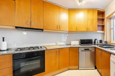 a kitchen with wooden cabinets and a stove top oven at Albufeira Coast Apartment by Double Ninety Stays in Albufeira