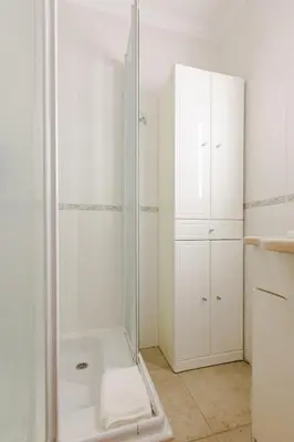 a bathroom with a shower and a white cabinet at Albufeira Coast Apartment by Double Ninety Stays in Albufeira