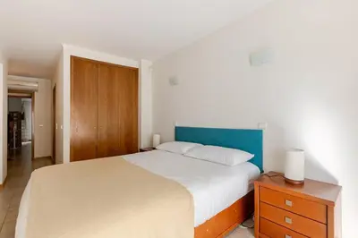a bedroom with a large bed and a wooden cabinet at Albufeira Coast Apartment by Double Ninety Stays in Albufeira