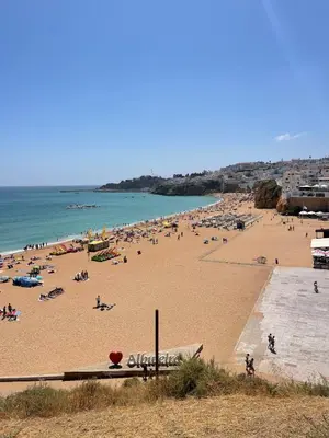 a beach with a lot of people on it at Albufeira Coast Apartment by Double Ninety Stays in Albufeira