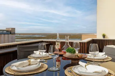 a table with chairs and wine glasses on a balcony at Top-Floor 2BR, Sea and city Views & Jacuzzi in Faro