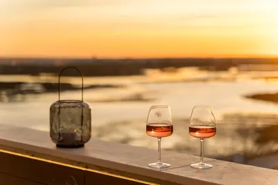 two glasses of wine sitting on a ledge with the sunset at Downtown, 1br with a first row view over the sea in Faro