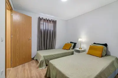 a room with two beds and a door with a window at Maison Jack in Albufeira