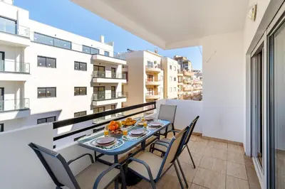 a table on a balcony with chairs and food on it at Sol & Mar Quarteira in Quarteira