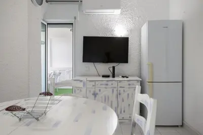 a kitchen with a table and a tv and a refrigerator at Sun & Sea Flat in Quarteira - Cozy Apartment Close to the Beach, by Hopstays in Quarteira