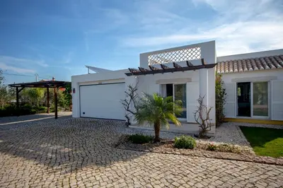a white house with a garage and a palm tree at Amazing villa in Albufeira - Alke Vida in Albufeira