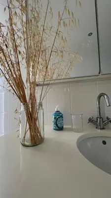 a bathroom counter with a vase with dry grass at The Lemon Tree House by IntiHolidays in Boliqueime