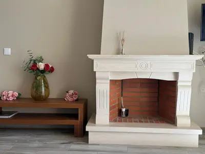 a white fireplace in a living room with a vase of flowers at Villa 23 - Ponta Grande Resort in Albufeira
