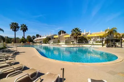 a large swimming pool with lounge chairs and palm trees at Villa 23 - Ponta Grande Resort in Albufeira