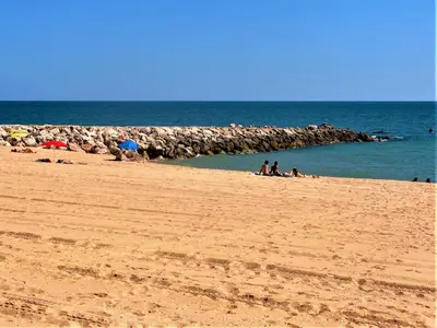 a group of people sitting on a beach near the ocean at Cavalo Preto Beach Resort Apt & Wi-Fi Nr Beach in Quarteira