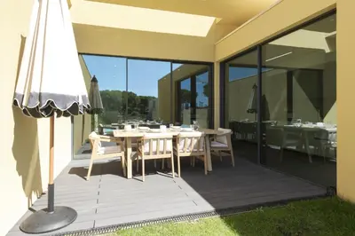 a dining table on a patio with glass doors at Vilamoura Parque - Luxury Villa with pool by HD in Vilamoura