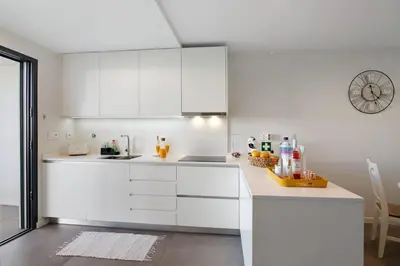 a kitchen with white cabinets and a clock on the wall at Casa do Sol and Golf - Vilamoura in Vilamoura