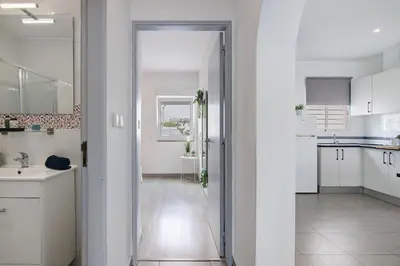 a white kitchen with a sink and a mirror at Casa Machadinho in Albufeira