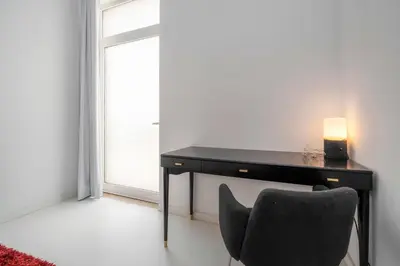 a bedroom with a desk and a bed with a red rug at Primavera House in Faro