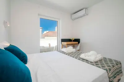 a white bedroom with a bed and a window at Primavera House in Faro